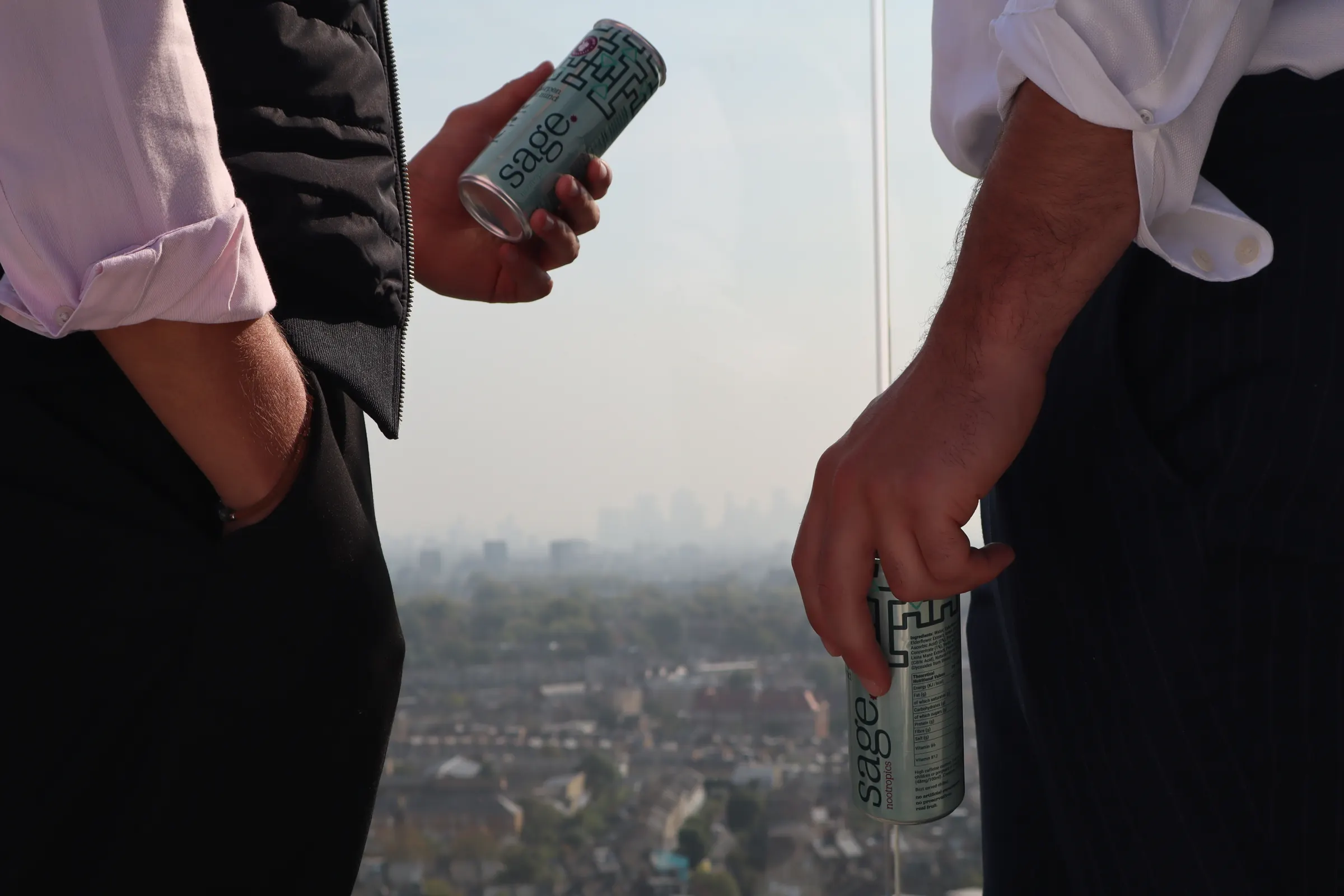 Two people on a rooftop terrace, cans of sage in hand